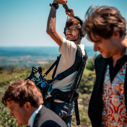 Bram van Kaauwen in action on a set, with two actors in the background.